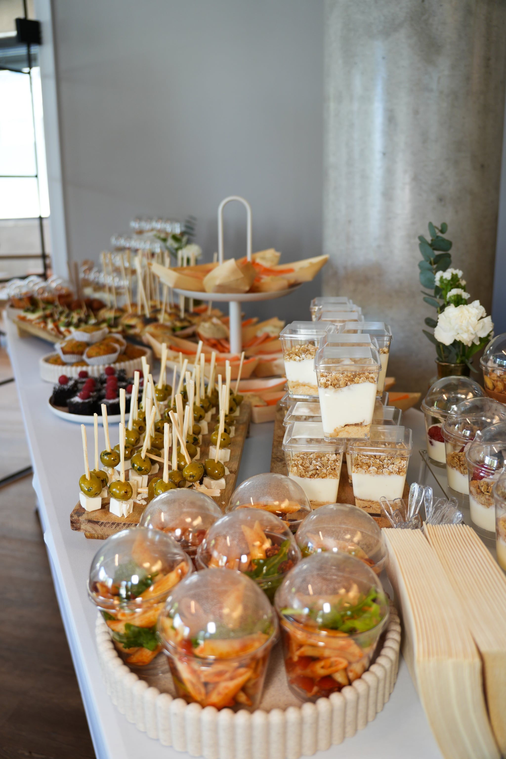 Snacks in kleinen Bechern und Schalen, Spießchen und Desserts auf einem langen Tisch