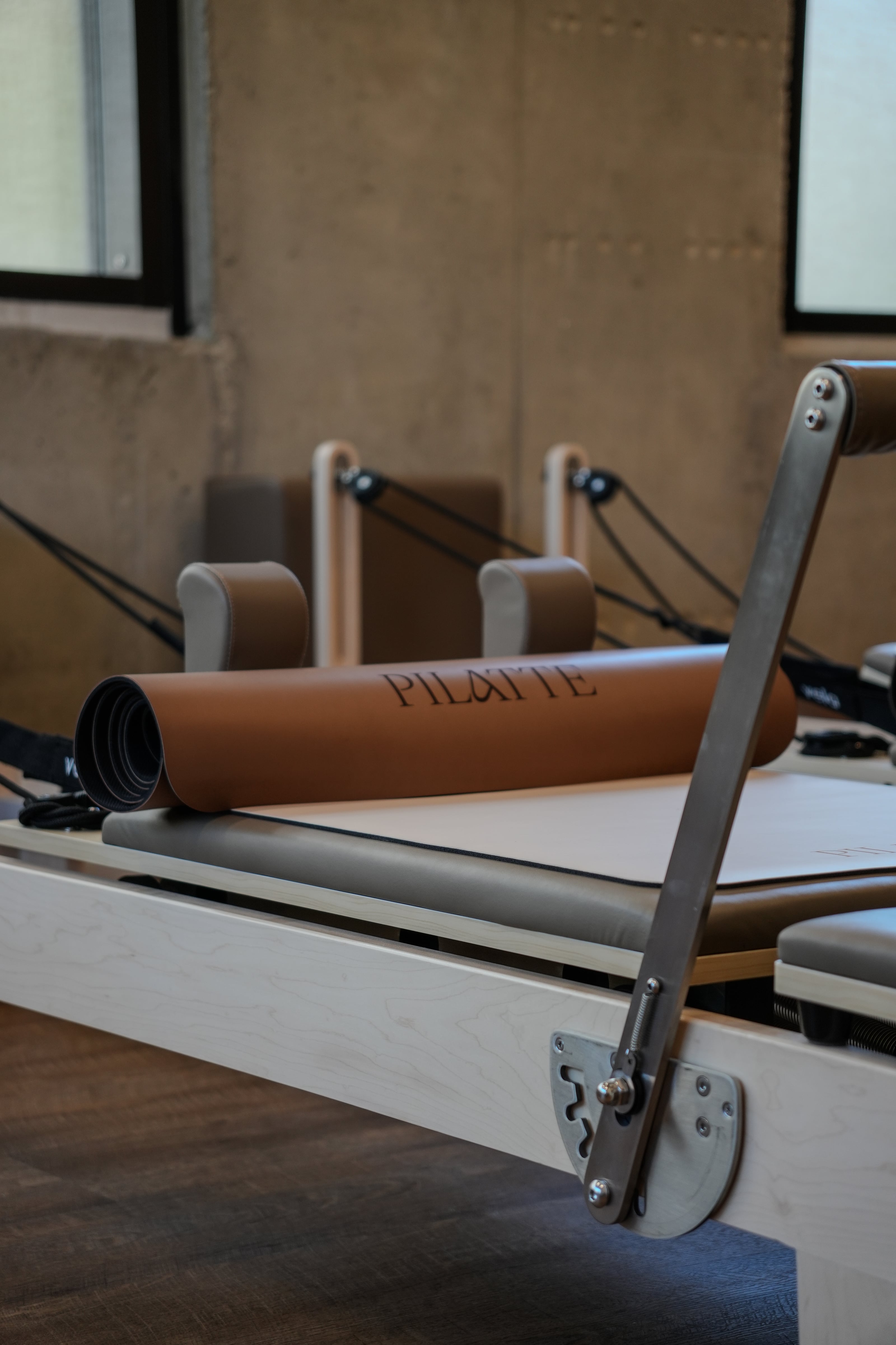 Gerollte Pilatte-Matte auf einem Reformer, davor die Fußstange