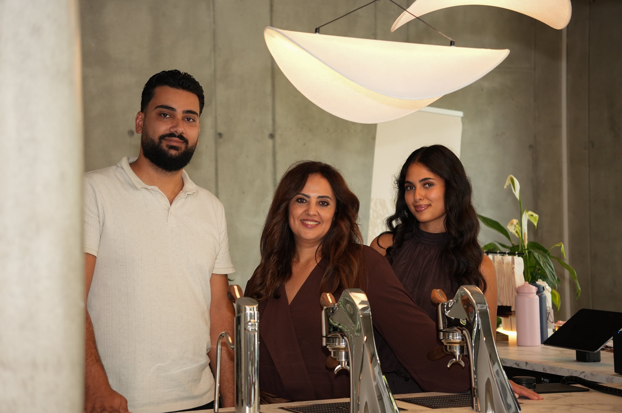 Serap, Sara und Cem hinter dem Tresen des Cafés, davor die Espressomaschine